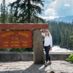 A woman beside the Natural Bridge sign