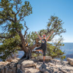 A person posing for a picture near a tree