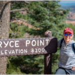 A woman taking a picture with the Bryce Point elevation sign