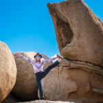 A woman balancing on one foot near a rock formation