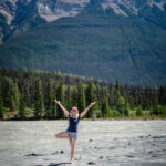 A woman standing on one foot near the Athabasca Falls