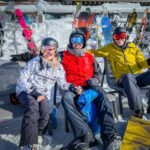 Three people in ski gear sitting down and resting