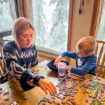 A woman doing a jigsaw puzzle with a boy