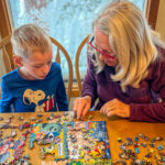 A woman helping a child finish a jigsaw puzzle