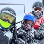 Three people in skiing gear covered in snow