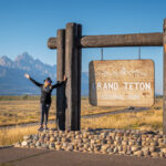 A woman posing at the sign of Grand Teton National Park