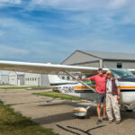 Two men in front of a small plane