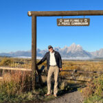 A man posing at the sign of the Bar Flying U J. Pierce Cunningham