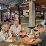 Three adults eating at the Calgary’s Farmer’s Market