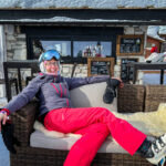 A woman in ski gear reclining on a café sofa  