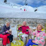 Three women sitting near ski cable cars