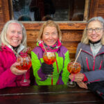 Three women holding glasses of alcohol