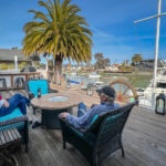 Two men sitting on chairs near a docked yacht