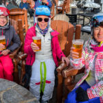Three women enjoying a drink while at a ski resort  
